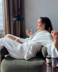 Vrouw in badjas met glas water en tallow creme in rustige ontspannen sfeer